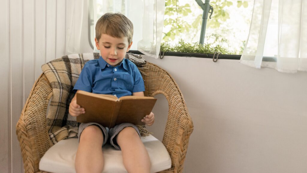 Niño disfrutando de la lectura de un libro en un sillón